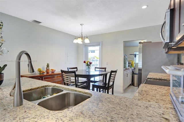 kitchen with a chandelier, visible vents, appliances with stainless steel finishes, a sink, and hanging light fixtures
