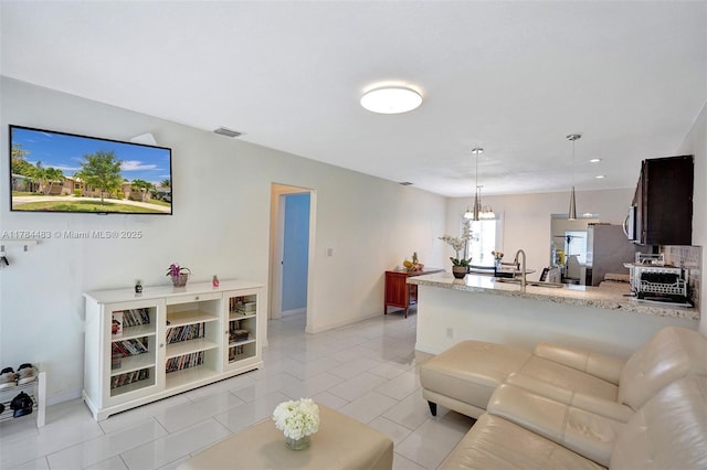 living room featuring light tile patterned flooring, visible vents, baseboards, and an inviting chandelier