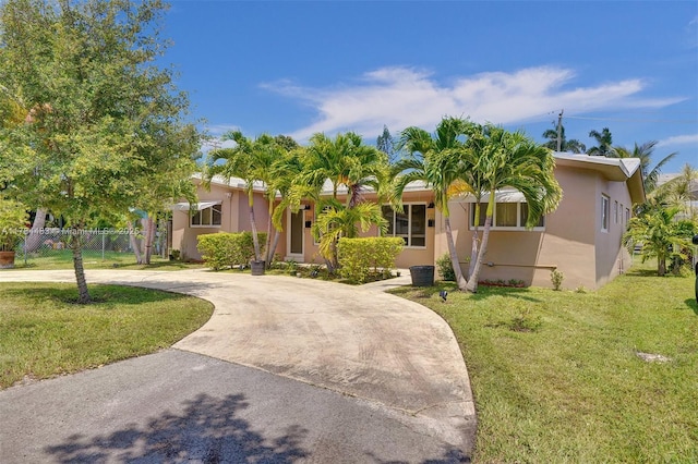 single story home with fence, a front yard, stucco siding, and curved driveway