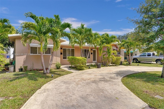 single story home featuring a front yard, driveway, and stucco siding