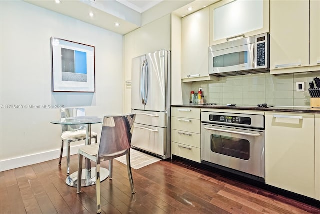 kitchen featuring dark countertops, recessed lighting, stainless steel appliances, dark wood-type flooring, and backsplash
