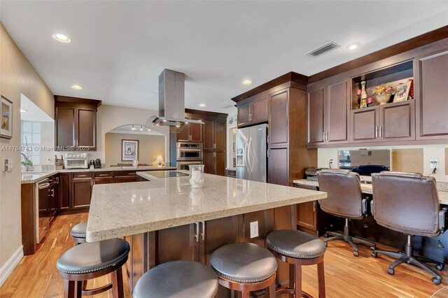 15801 SW 77th Ct, Palmetto Bay, FL 33157 - kitchen with appliances with stainless steel finishes, light wood-type flooring, a kitchen breakfast bar, a kitchen island, and light stone counters