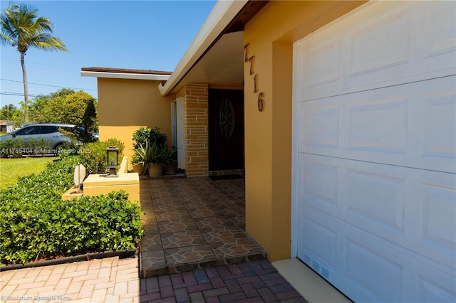 entrance to property featuring a garage and stucco siding