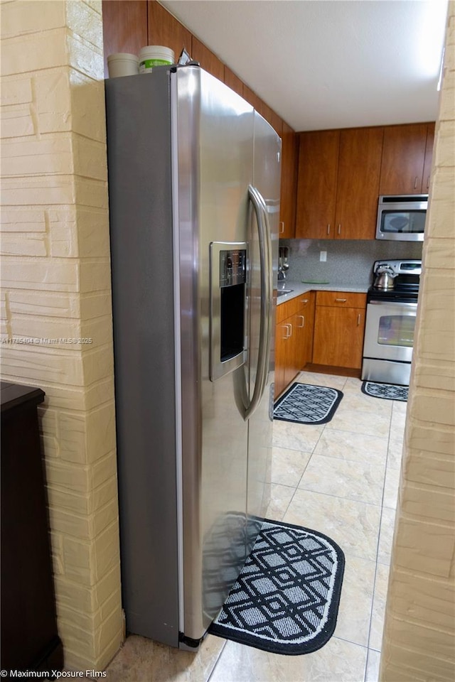 kitchen featuring stainless steel appliances, brown cabinets, and light countertops