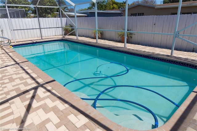 view of swimming pool featuring a fenced backyard, glass enclosure, a fenced in pool, and a patio