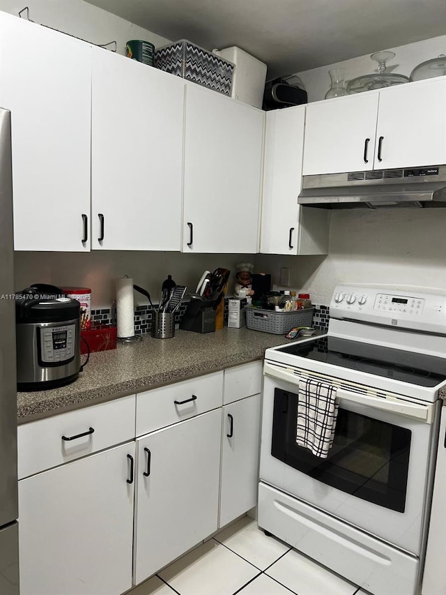 kitchen with light tile patterned floors, white cabinetry, electric stove, and under cabinet range hood