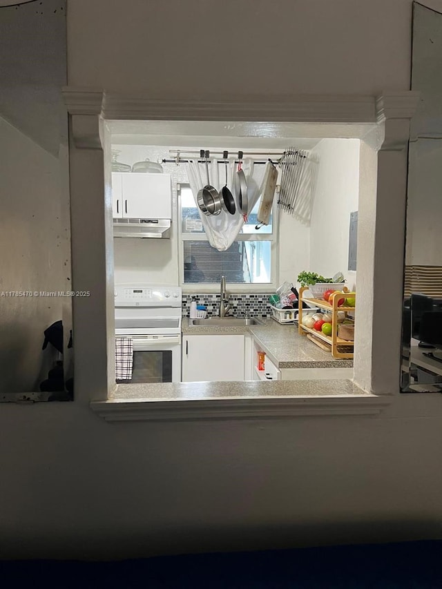 kitchen with white cabinets, under cabinet range hood, light countertops, a sink, and electric stove