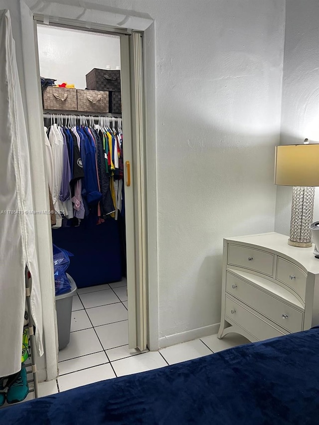 bedroom featuring light tile patterned floors, a spacious closet, a closet, and baseboards