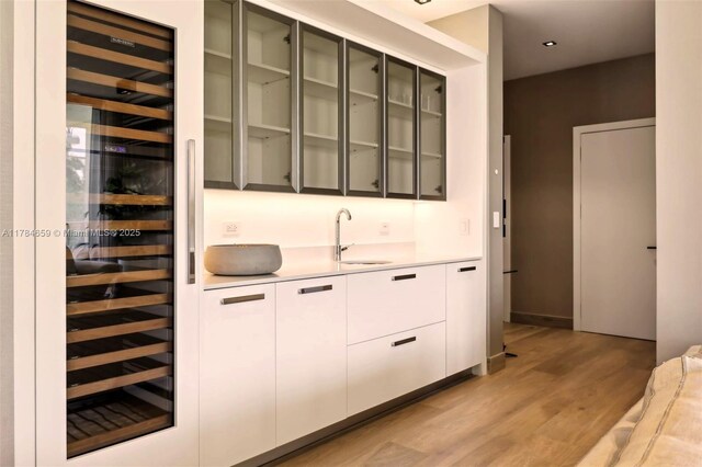 3581 E Glencoe St Unit 309, Miami, FL 33133 - bar featuring a sink, light wood-style flooring, indoor wet bar, and beverage cooler