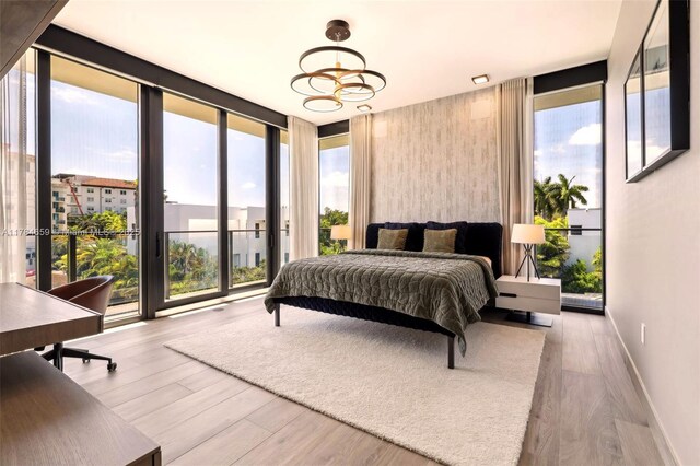 3581 E Glencoe St Unit 309, Miami, FL 33133 - bedroom featuring multiple windows, wood finished floors, a wall of windows, and baseboards