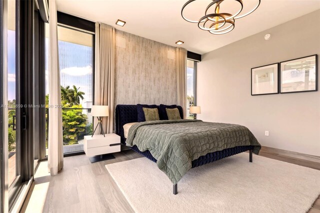 3581 E Glencoe St Unit 309, Miami, FL 33133 - bedroom with multiple windows, floor to ceiling windows, a chandelier, and wood finished floors