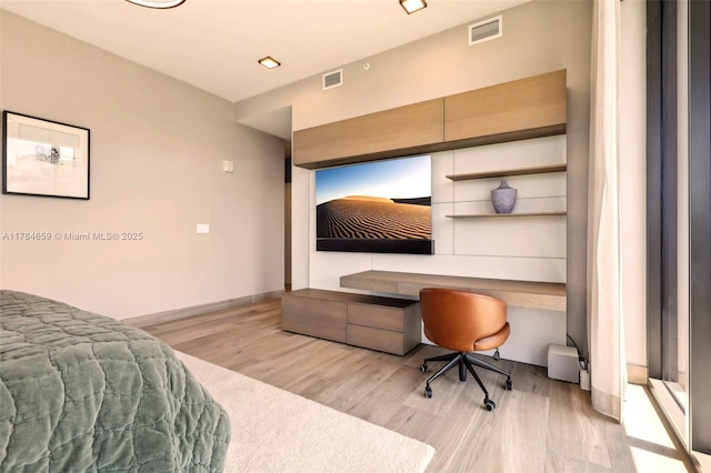 3581 E Glencoe St Unit 309, Miami, FL 33133 - bedroom with built in study area, visible vents, and wood finished floors