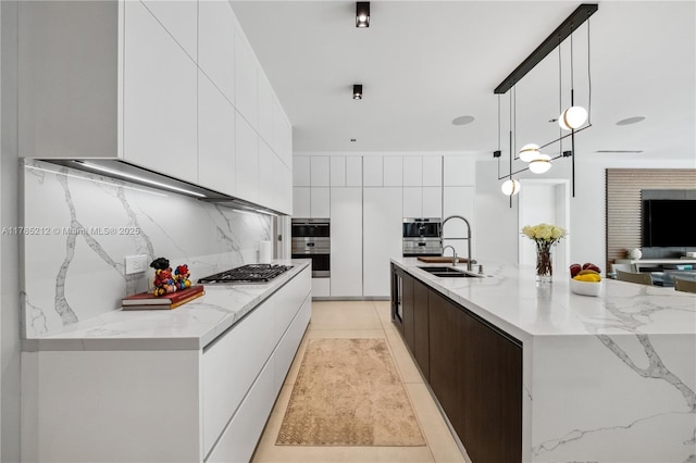 8825 SW 64th Ct, Pinecrest, FL 33156 - kitchen featuring modern cabinets, a sink, stainless steel gas stovetop, decorative backsplash, and white cabinetry