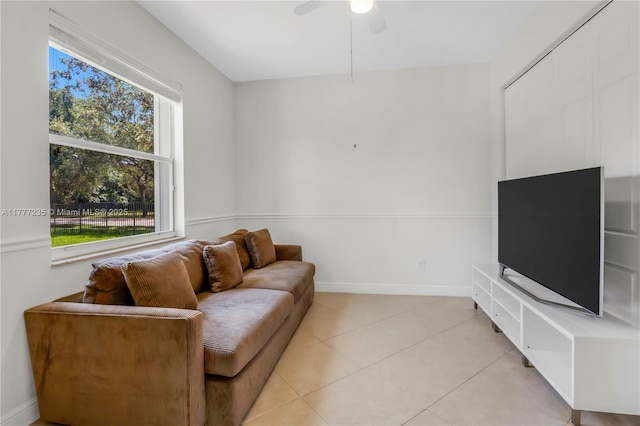 living area with ceiling fan, baseboards, and light tile patterned flooring