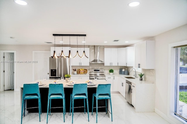 kitchen with visible vents, wall chimney exhaust hood, a sink, stainless steel appliances, and decorative backsplash