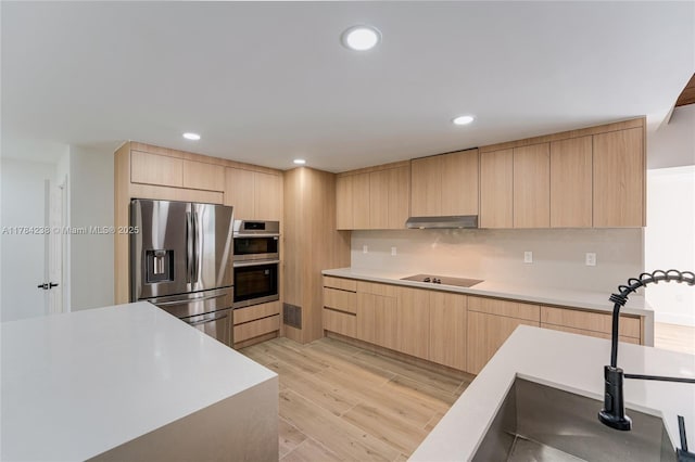 15201 SW 87th Ct, Palmetto Bay, FL 33157 - kitchen with modern cabinets, light wood-style flooring, light brown cabinetry, under cabinet range hood, and stainless steel appliances