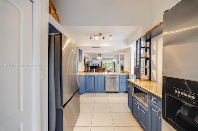 kitchen featuring light tile patterned floors, light countertops, appliances with stainless steel finishes, and blue cabinets
