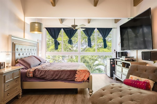 bedroom with wood finished floors, multiple windows, and beam ceiling