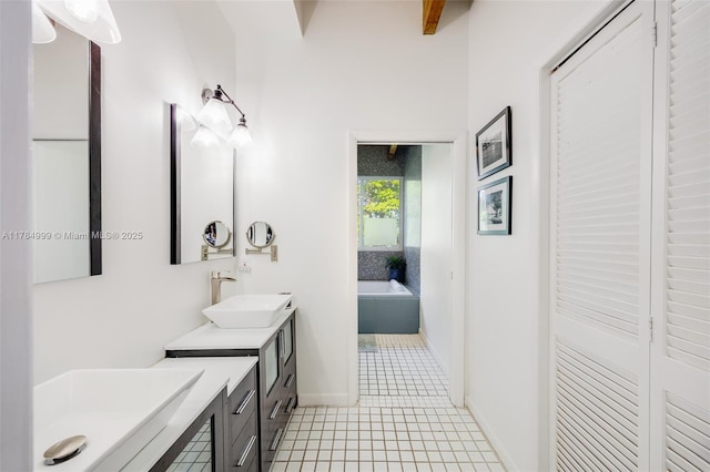 bathroom with two vanities, a bath, tile patterned flooring, a sink, and baseboards