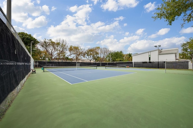 view of tennis court featuring community basketball court and fence