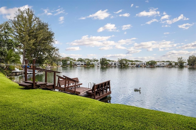 dock area with boat lift, a yard, and a water view
