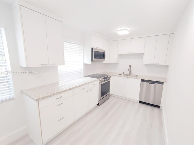 60 Burgundy B 60, Delray Beach, FL 33484 - kitchen with a sink, white cabinetry, light stone countertops, light wood-style flooring, and stainless steel appliances