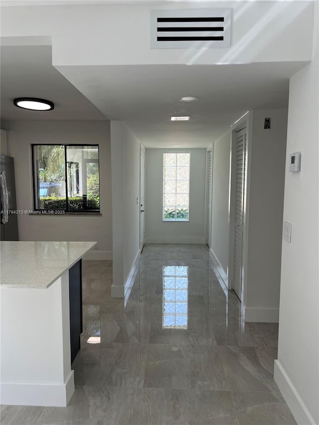 corridor featuring marble finish floor, visible vents, and baseboards
