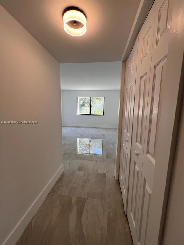 hallway with marble finish floor and baseboards