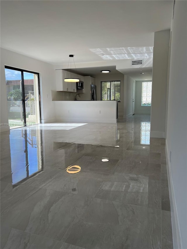 unfurnished living room with a sink, visible vents, marble finish floor, and baseboards