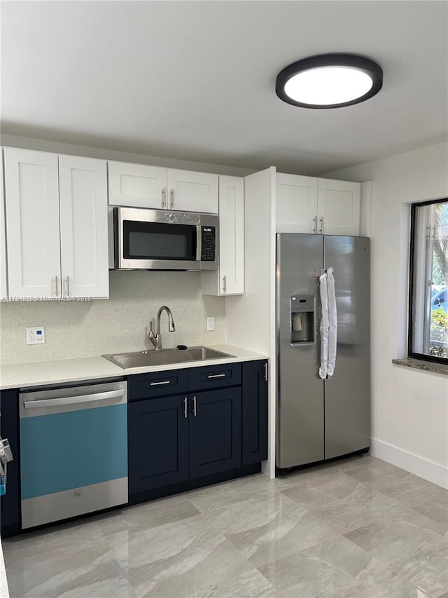 kitchen featuring stainless steel appliances, white cabinets, light countertops, and a sink