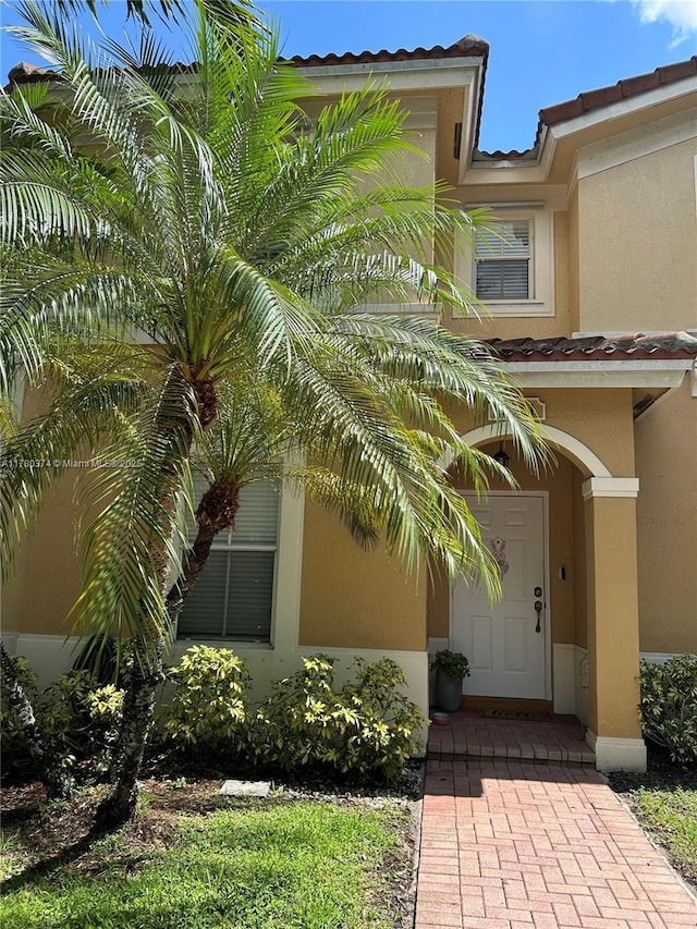 view of exterior entry with a tile roof and stucco siding