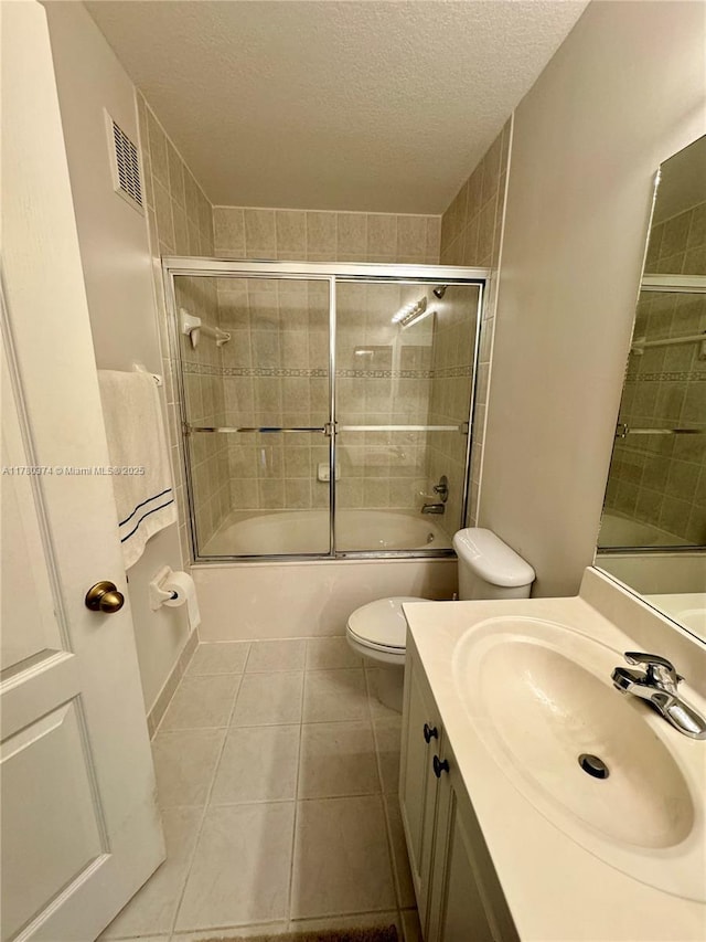 bathroom with visible vents, toilet, a textured ceiling, shower / bath combination with glass door, and tile patterned floors