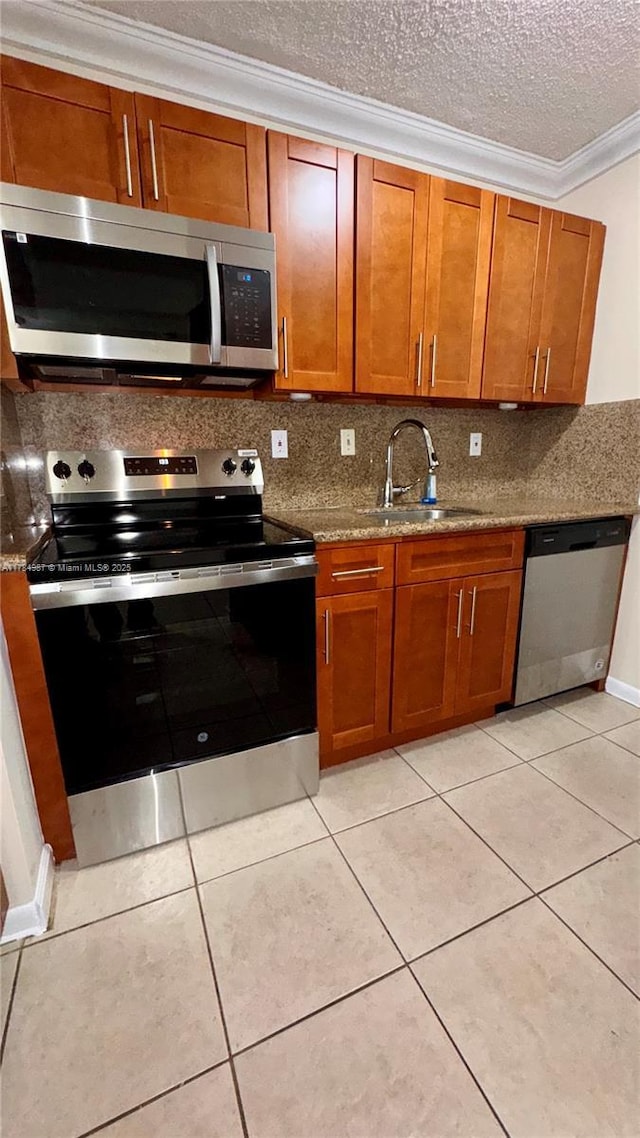 10795 SW 108th Ave Unit 103, Miami, FL 33176 - kitchen with crown molding, brown cabinetry, tasteful backsplash, a sink, and stainless steel appliances