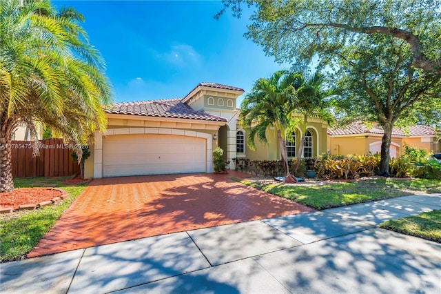mediterranean / spanish home featuring stucco siding, a tile roof, decorative driveway, and a garage