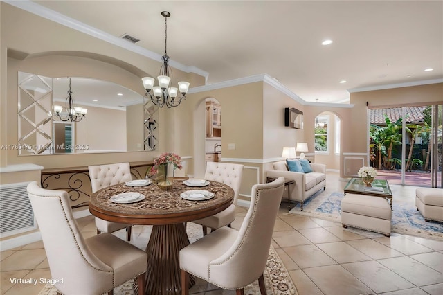 dining space with a chandelier, arched walkways, crown molding, a wainscoted wall, and light tile patterned flooring