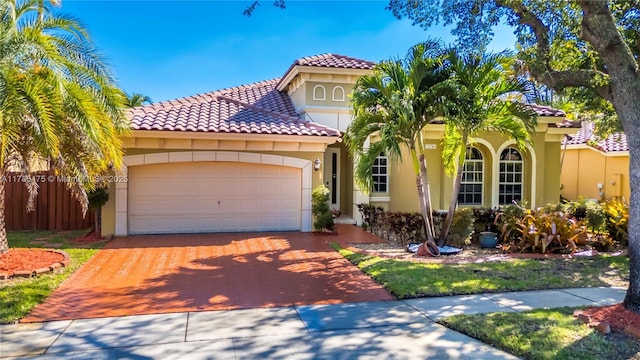 mediterranean / spanish-style home with stucco siding, decorative driveway, an attached garage, a tile roof, and fence