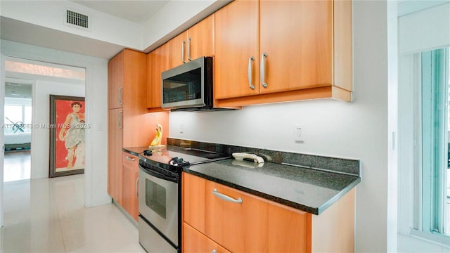 kitchen featuring light tile patterned floors, dark countertops, visible vents, and appliances with stainless steel finishes