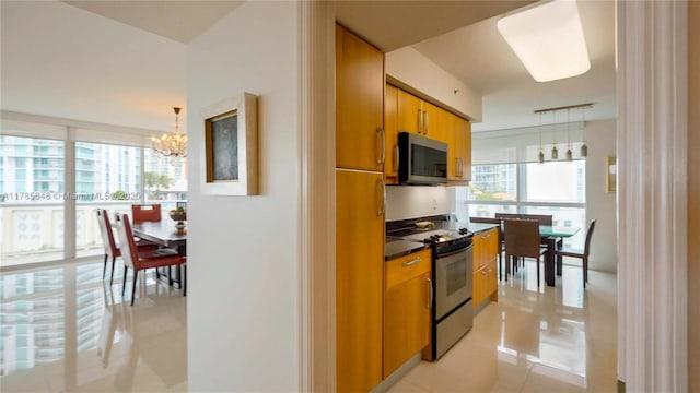 kitchen featuring brown cabinets, dark countertops, appliances with stainless steel finishes, and an inviting chandelier