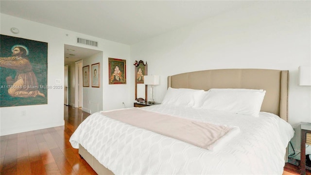 bedroom with baseboards, wood finished floors, and visible vents
