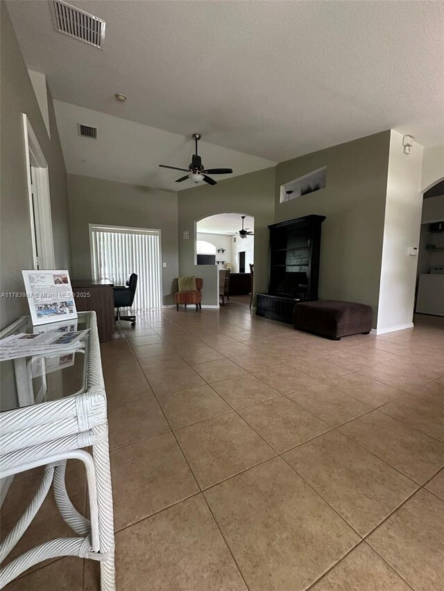 1214 SW Patricia Ave, Port St Lucie, FL 34953 - tiled living area with a ceiling fan, arched walkways, a textured ceiling, vaulted ceiling, and baseboards