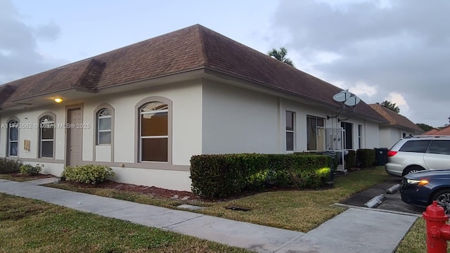 11975 Sturbridge Ln, Wellington, FL 33414 - view of property exterior featuring a shingled roof, stucco siding, and a lawn