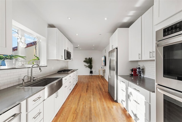 kitchen featuring a sink, decorative backsplash, appliances with stainless steel finishes, and white cabinetry