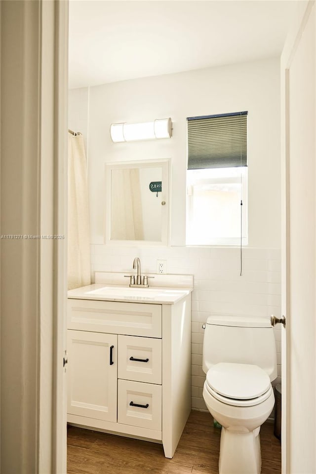 bathroom featuring vanity, tile walls, toilet, and wood finished floors