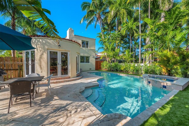 view of swimming pool with a patio area, fence, french doors, an in ground hot tub, and a fenced in pool