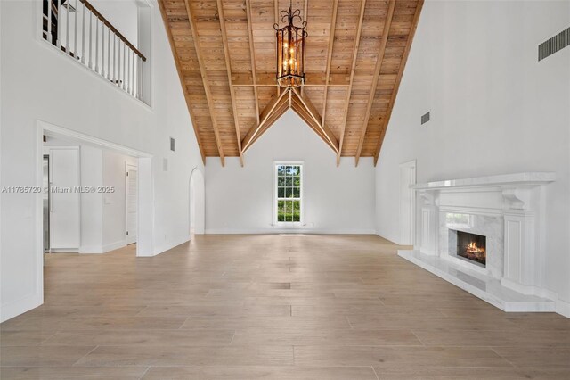6320 Hancock Rd, Southwest Ranches, FL 33330 - unfurnished living room with a wooden ceiling with exposed beams, high vaulted ceiling, a premium fireplace, a chandelier, and light wood finished floors
