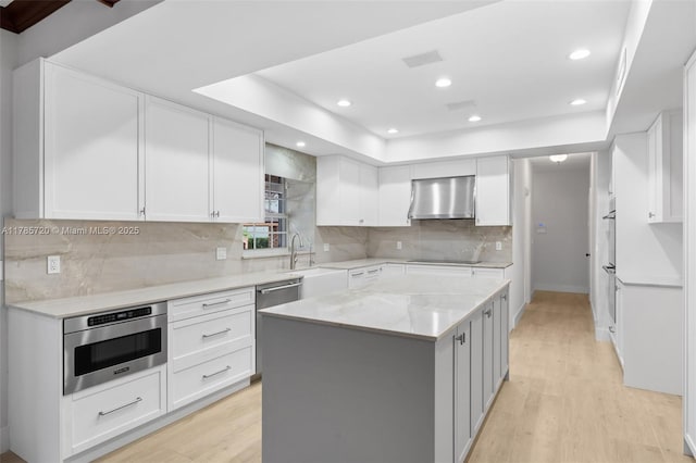 6320 Hancock Rd, Southwest Ranches, FL 33330 - kitchen with wall chimney exhaust hood, stainless steel appliances, light wood-style flooring, white cabinets, and a center island
