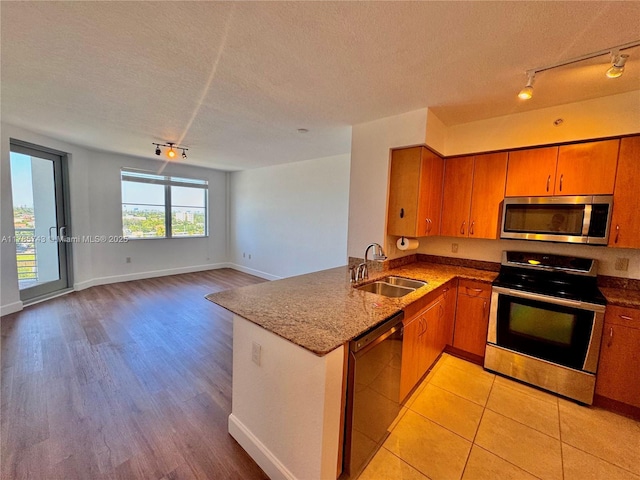 kitchen with a textured ceiling, rail lighting, appliances with stainless steel finishes, and a sink