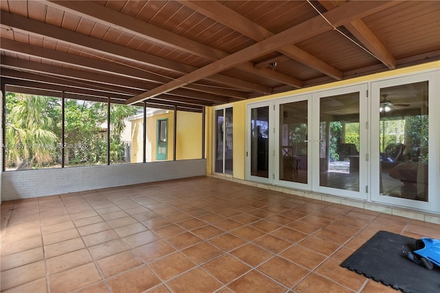 unfurnished sunroom featuring beamed ceiling, french doors, and a wealth of natural light