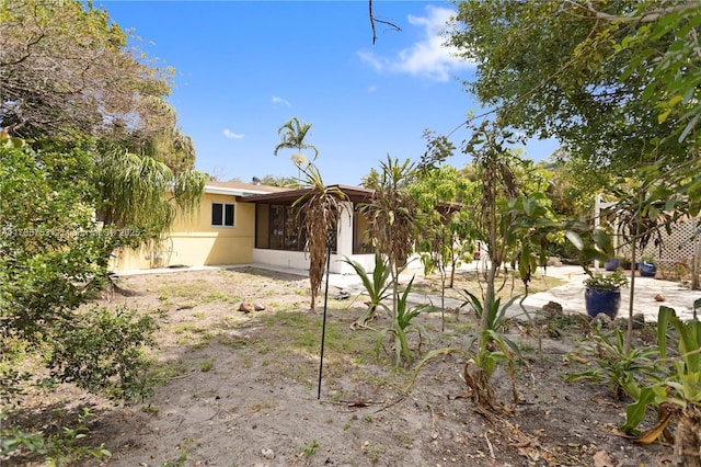 rear view of property featuring a sunroom and stucco siding