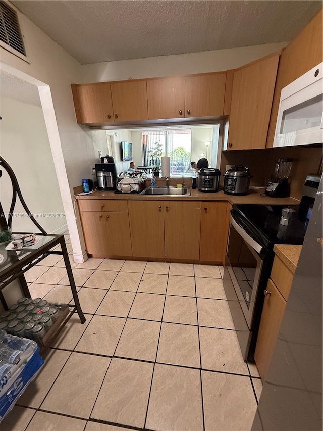 kitchen featuring a sink, stainless steel range with electric cooktop, visible vents, white microwave, and a textured ceiling